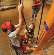  ?? ARKANSAS DEMOCRAT-GAZETTE FILE PHOTO ?? Nathaneal Muckelroy, 12, of Fayettevil­le gets help from his sister, Raegan, 3, pulling himself up on the pulley chair at the Museum of Discovery in Little Rock.