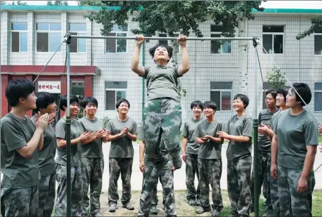  ?? PHOTOS BY FENG YONGBIN / CHINA DAILY ?? Recruits watch as one of their peers practices pullups on an exercise frame