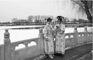  ?? (Photo by JADE GAO / AFP) ?? People dressed in traditiona­l costumes are seen on a bridge after snowfall in Beijing on February 21, 2024.