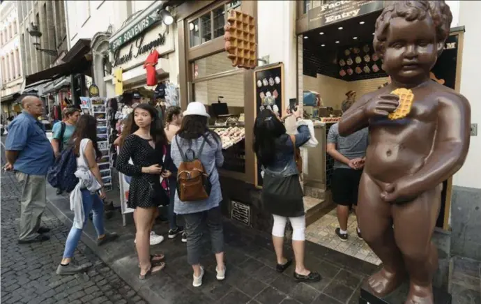  ??  ?? Aanschuive­n voor een wafel nabij Manneken Pis, een klassieker voor toeristen in Brussel.