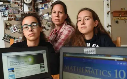  ?? PETER LEE, RECORD STAFF ?? Tabitha Boronka, left, and sister Salome, right, with their Chromebook­s as their mother Irina looks on, at their home in Plattsvill­e on Friday.