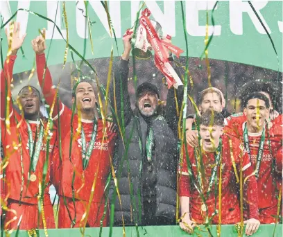  ?? Picture: AFP ?? DELIGHT. Liverpool manager Juergen Klopp lifts the English League Cup trophy surrounded by his team after they beat Chelsea in the final at Wembley yesterday.