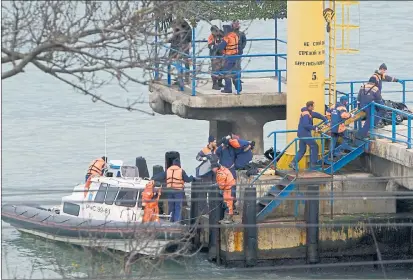  ??  ?? GRIM TASK: Russian rescue workers collect wreckage from the crashed plane as it arrives at a pier just outside Sochi.