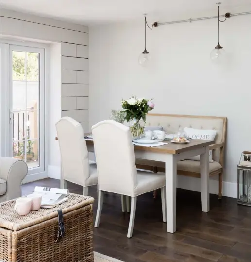  ??  ?? DINING AREA Among furniture from the couple’s former home is the Windsor table and pale linen chairs, from Bramblecre­st. The upholstere­d dining bench is from Homesense. Globe pendant lights hung from a metal conduit tube add an industrial touch