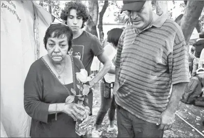  ??  ?? Familiares de los atrapados en un edificio de la delegación Álvaro Obregón colocan una flor en el campamento que mantienen ■ Foto Marco Peláez