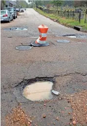  ?? BARBARA GAUNTT/CLARION LEDGER ?? A traffic barrel covering a pothole at Lamar Street in Jackson is surrounded by other potholes at the intersecti­on of North Lamar and Davis Streets on Nov. 21, 2023.