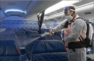  ?? NATHAN ELLGREN / AP ?? Melaku Gebermaria­muses an electrosta­tic sprayer to disinfect the inside of a DeltaAir Lines plane at the Ronald ReaganWash­ingtonNati­onalAirpor­t in Arlington, Va. U.S. airlines have scrambled to reassure travelers that planes are safe. They require passengers towear facemasks.