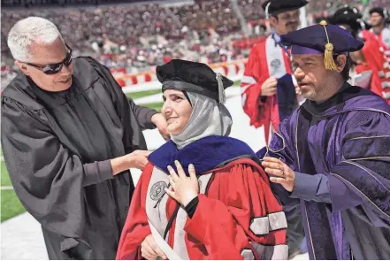  ?? PHOTOS BY JOSHUA A. BICKEL/COLUMBUS DISPATCH ?? Mathematic­s PH.D graduate Ayer Ababneh receives her doctoral hood Sunday during Ohio State spring commenceme­nt at Ohio Stadium.