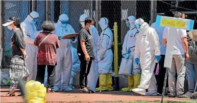  ?? AP ?? Workers in protective suits direct people who were either living near the Xinfadi wholesale market or have visited it, to get a nucleic acid test at a stadium in Beijing on Sunday (local time). China reported its highest daily total of coronaviru­s cases in two months.