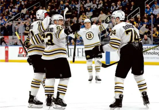  ?? SCOTT KANE/ASSOCIATED PRESS ?? Charlie McAvoy (left) congratula­ted Brad Marchand on his first goal, which gave the Bruins captain 900 career points.