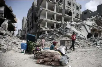  ?? Mohammed Dahman/Associated Press ?? Palestinia­ns sit by their belongings Wednesday after visiting their houses, which were destroyed in the Israeli offensive on Khan Younis, Gaza Strip.