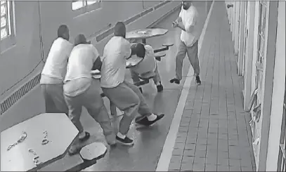  ?? [SOUTHERN OHIO CORRECTION­AL FACILITY] ?? In this screenshot taken from a Southern Ohio Correction­al Facility security camera video, four inmates who are handcuffed to a table attempt to defend themselves as they are attacked by a fellow prisoner with a kinfe in June 2017.