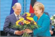  ?? REUTERS ?? Finance Minister Olaf Scholz receives flowers from German Chancellor Angela Merkel in Berlin.