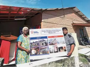  ?? — Bernama ?? Well-deserved comfort: Vejaya and Paramaanan­than standing outside Vejaya’s repaired home.