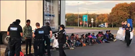  ??  ?? Lined up: The immigrants are interviewe­d by police at Farthing Corner Services on the M2 in Kent