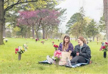  ?? KENNETH FERRIERA/LINCOLN JOURNAL STAR ?? Mother’s Day: Christine Scott, left, and daughter Keisha Scott share a picnic at the grave of Christine’s mother and father Sunday in Lincoln, Neb.“My mother died suddenly of a heart condition, and then several weeks later, dad died of what the doctors called a grief response,” Christine Scott said. Her parents died in 2020.