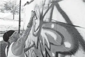  ?? AKRON BEACON JOURNAL ?? Artist Chris Harden works on a butterfly as he paints a mural Tuesday in memory of the late Janine Surgen in Akron.