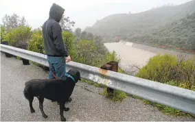  ?? DAN HONDA/STAFF ?? A man and his dog watch the spillway at Anderson Reservoir in the wettest winter in 20 years.