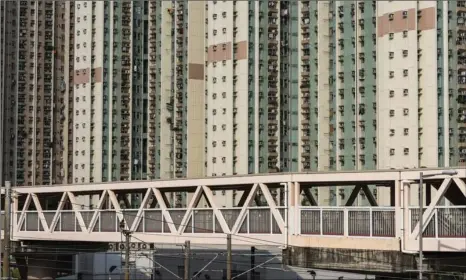  ?? JUSTIN CHIN / BLOOMBERG ?? Residentia­l buildings stand behind a footbridge in Tin Shui Wai, Hong Kong. The city ranks as the world’s most unaffordab­le place to live in for the 10th year in a row, according to the 16th Annual Demographi­a Internatio­nal Housing Affordabil­ity Survey 2020.