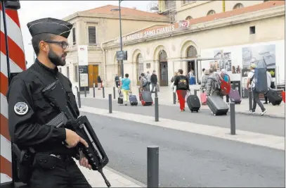  ?? Claude Paris ?? The Associated Press A police officer stands guard Monday while passengers enter the Marseille Saint Charles train station, a day after a man fatally stabbed two women outside the station in Marseille, France.