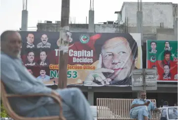  ??  ?? Pakistani men sit near a poster of Khan in Islamabad. — AFP photo