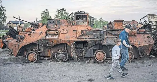  ?? GENTILEZA PABLO TOSCO ?? POSTAL. Un niño camina junto a un adulto frente a un tanque destruido, en Bucha, ciudad arrasada por los rusos. La guerra está golpeando con dureza a las infancias en Ucrania.