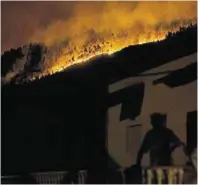  ??  ?? A man watches the fires above the village of Avelar