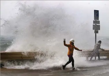  ?? ROY LIU / CHINA DAILY ?? A man experience­s the power of a large wave on the waterfront in Sai Wan as Typhoon Haima swept through Hong Kong on Friday.