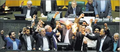  ??  ?? The Associated Press Iranian lawmakers burn two pieces of paper representi­ng the U.S. flag and the nuclear deal as they chant slogans against the U.S. on Wednesday at the parliament in Tehran, Iran.