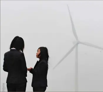  ?? Getty Images via TNS ?? Employees of a wind farm developed by state-owned China Energy Conservati­on Investment Corp take in the view of towering wind turbines in Zhangbei, north of Beijing in Hebei province.