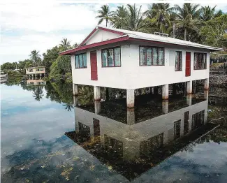  ?? ?? Wer seine Häuser nicht auf Stelzen baut, ist auf Tuvalu den Wassermass­en ausgeliefe­rt