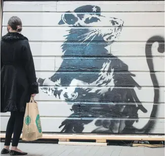  ?? THE CANADIAN PRESS ?? A woman views the Saving Banksy exhibit at Yorkville Village in Toronto this week.