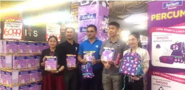  ??  ?? Area sales executive for Fonterra brands, Ho Kuok Ping (second left) and the promoters showing one of the Fonterra brands, Anmum Essential and some of the freebies that customers will get if buying at certain value.