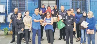  ??  ?? DEMI INTEGRITI: Ismail (tiga kiri) menderma bungkusan coklat pemberian netizen kepada orang ramai di hadapan Balai Polis Sentral Kuching semalam.