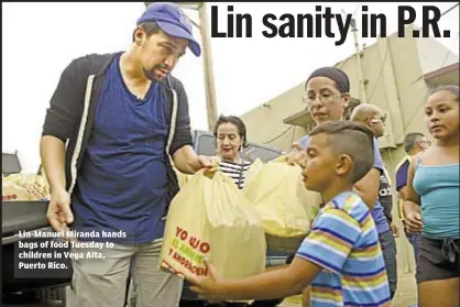  ??  ?? Lin-Manuel Miranda hands bags of food Tuesday to children in Vega Alta, Puerto Rico.