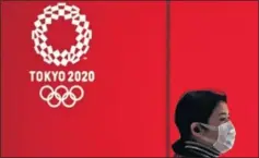  ??  ?? Una ciudadana de Tokio, ante un cartel con el logo de los Juegos.