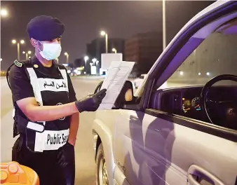  ?? SPA ?? Security official enforcing the curfew to limit the spread of coronaviru­s check a motorist in Jeddah on Saturday.