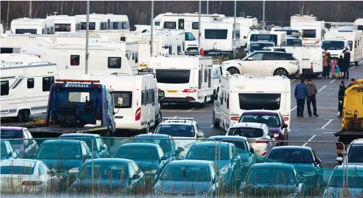  ??  ?? Car park full... of caravans: The travellers’ vehicles dominate the scene at a railway station in Cambridge yesterday
