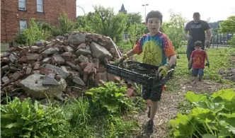  ?? Rebecca Lessner/Post-Gazette ?? Jordan Block, 9, left, carries compost in a community garden in East Liberty with his brother, Benny, 2, and father, Zack Block, in June 2018.