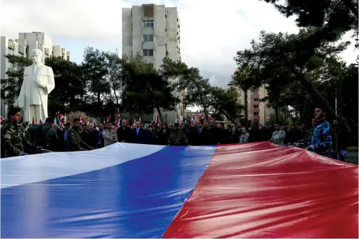  ?? (Yamam al Shaar/Reuters) ?? SYRIAN UNIVERSITY students in Damascus hold a giant Russian flag at a pro-Russia rally following the invasion of Ukraine.