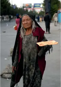  ?? Photos: AP ?? Left, food is becoming scarce for many in Kabul, and the city’s once-busy streets have begun to hollow out as Taliban fighters stand guard, right.
