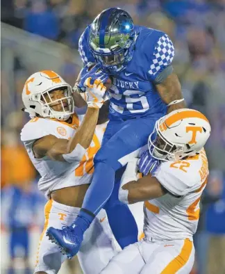  ?? THE ASSOCIATED PRESS ?? Snell is sandwiched by Tennessee defensive backs Nigel Warrior, left, and Micah Abernathy during the first half. Snell rushed for 180 yards on 27 carries, including three touchdowns.