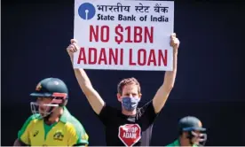  ?? Photograph: David Gray/AFP/Getty Images ?? Aaron Finch and David Warner watch as a climate activist protests against the Adani coal project in Queensland.