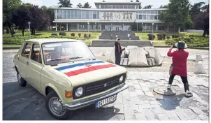  ??  ?? Visitors, standing next to a vintage car, take pictures in front of the Museum of Yugoslavia in Belgrade.