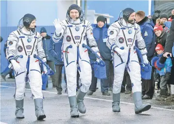  ?? — Reuters photo ?? Internatio­nal Space Station (ISS) crew members (from right) David Saint-Jacques, Oleg Kononenko and Anne McClain walk after donning space suits shortly before their launch at the Baikonur Cosmodrome.