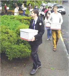  ??  ?? WASHINGTON: Carbon Washington campaign organizer Ben Silesky, left, leads a group of supporters and organizati­on members into the Elections Office for the Washington Secretary of State in Olympia, Washington to deliver signatures in support of putting...