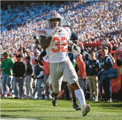  ?? SCOTT TAETSCH/GETTY ?? OSU’s TreVeyon Henderson silences the PSU crowd as he runs for a touchdown Saturday in State College, Pennsylvan­ia.