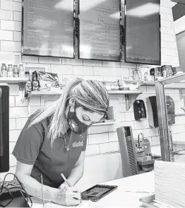  ?? Elizabeth Conley / Staff photograph­er ?? Greisy Perekalski, co-owner of Argentina Empanada Factory, takes an online order at the Houston restaurant in August.