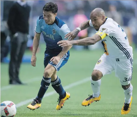  ?? DARRYL DYCK/ THE CANADIAN PRESS ?? The Vancouver Whitecaps’ Nicolas Mezquida, left, moves the ball past the Los Angeles Galaxy’s Nigel de Jong in Vancouver last Saturday. Mezquida started up front, but then dropped back to the midfield after Matias Laba received a red card.