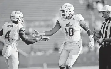  ?? [PHOTO BY JESSIE WARDARSKI, TULSA WORLD] ?? Quarterbac­k Chad President, 10, and running back D’Angelo Brewer, 4, celebrate a TU touchdown against LouisianaL­afayette on Saturday at H.A. Chapman Stadium.